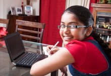 Girl working on her laptop at home on the dining room table