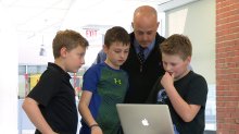 Buddy Berry looks at a computer with students. 