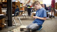 A boy works on the floor in his class.