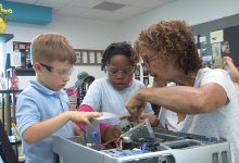 Teacher works with young children to take apart a computer.