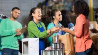 Three teenagers with one adult handing out canned foods to those in need.