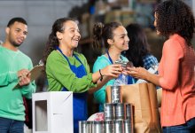 Three teenagers with one adult handing out canned foods to those in need.