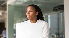 A professional Black woman looks out the window with a reflective expression