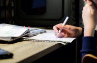 High school student copying notes from a textbook