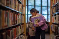 Two students picking out books at the library