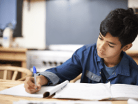 A photo of an elementary-school boy writing in his notebook.